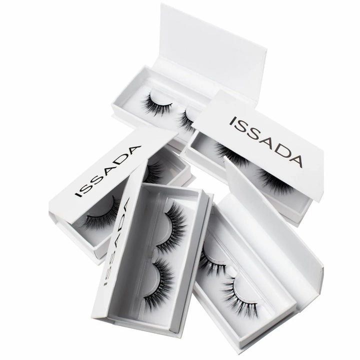 Multiple pairs of ISSADA Lashed Up eyelashes in white boxes, designed for dramatic volume and reusable wear