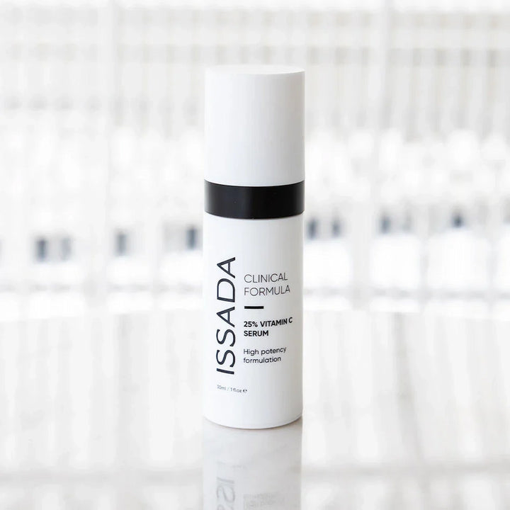 ISSADA 25% Vitamin C Serum standing on reflective surface, high potency formula designed to brighten skin and reduce fine lines.