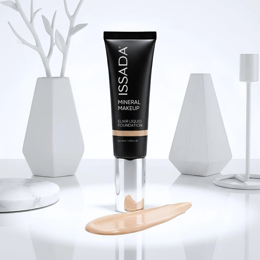 ISSADA Elixir Liquid Foundation tube displayed upright with a beige foundation swatch on a glossy white surface.