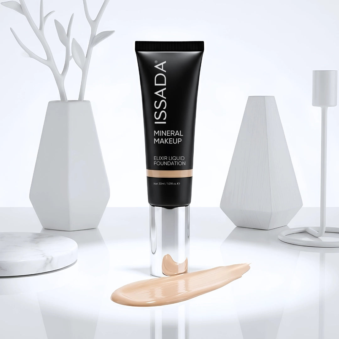 ISSADA Elixir Liquid Foundation tube displayed upright with a beige foundation swatch on a glossy white surface.