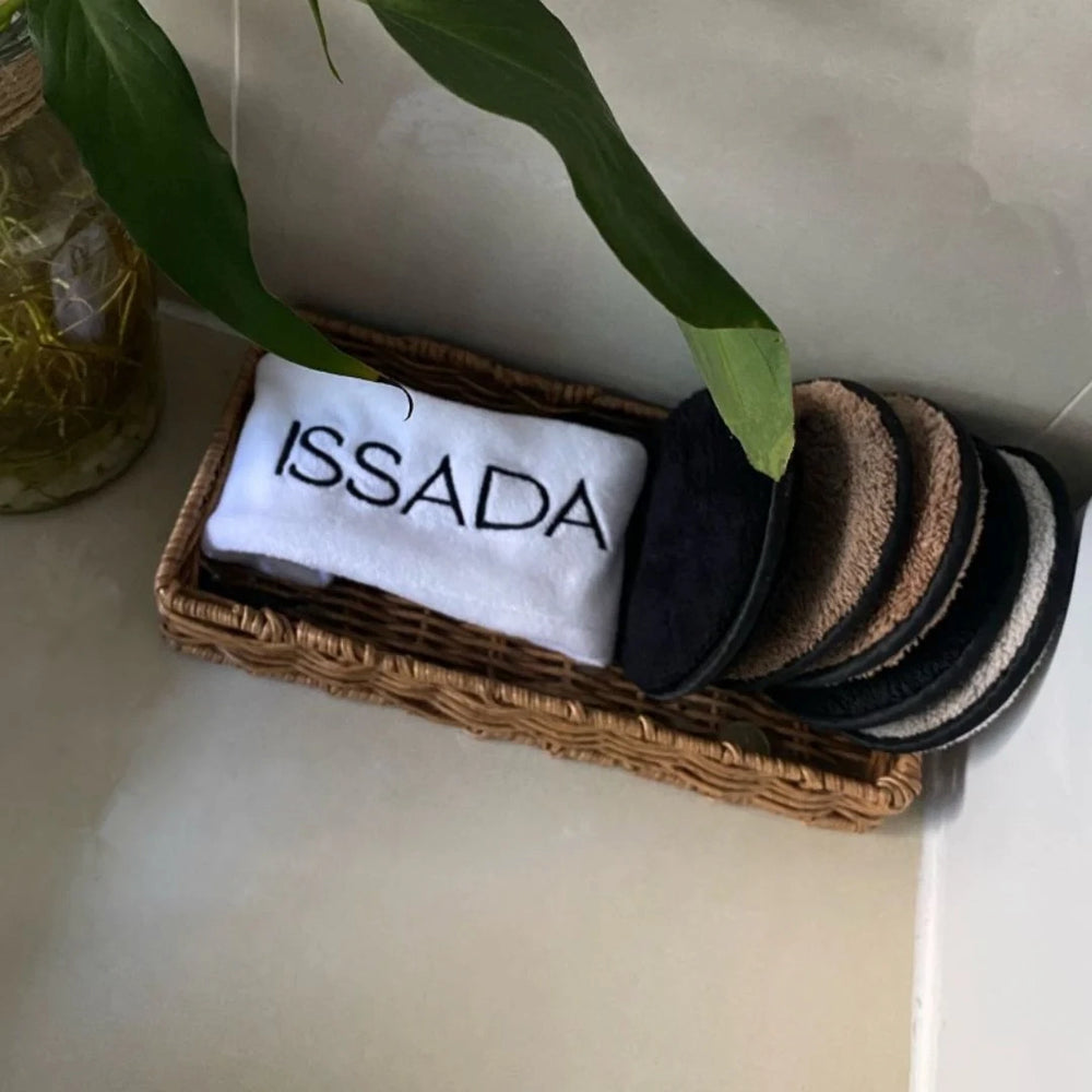 Issada cosmetic headband with reusable cleansing pads displayed in a wicker basket, eco-friendly skincare accessories.