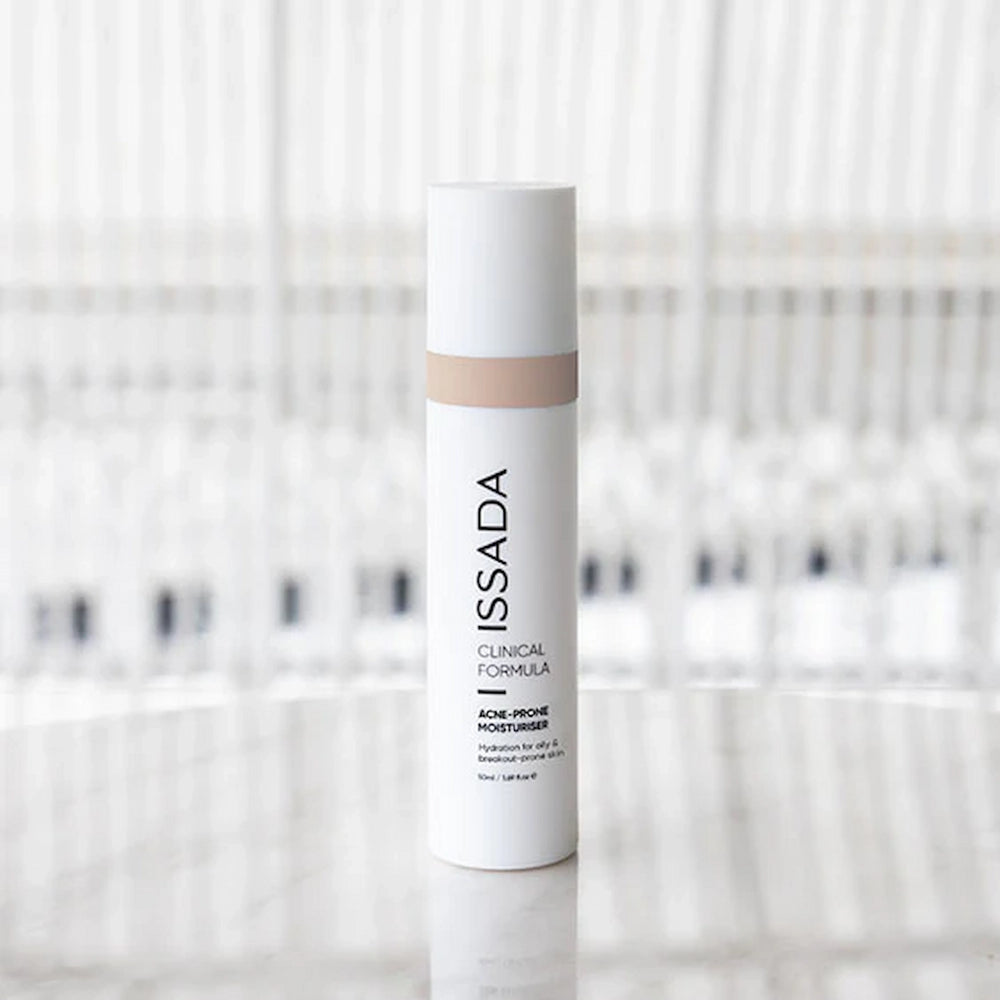ISSADA Clinical Formula Acne-Prone Moisturiser bottle standing on reflective surface.