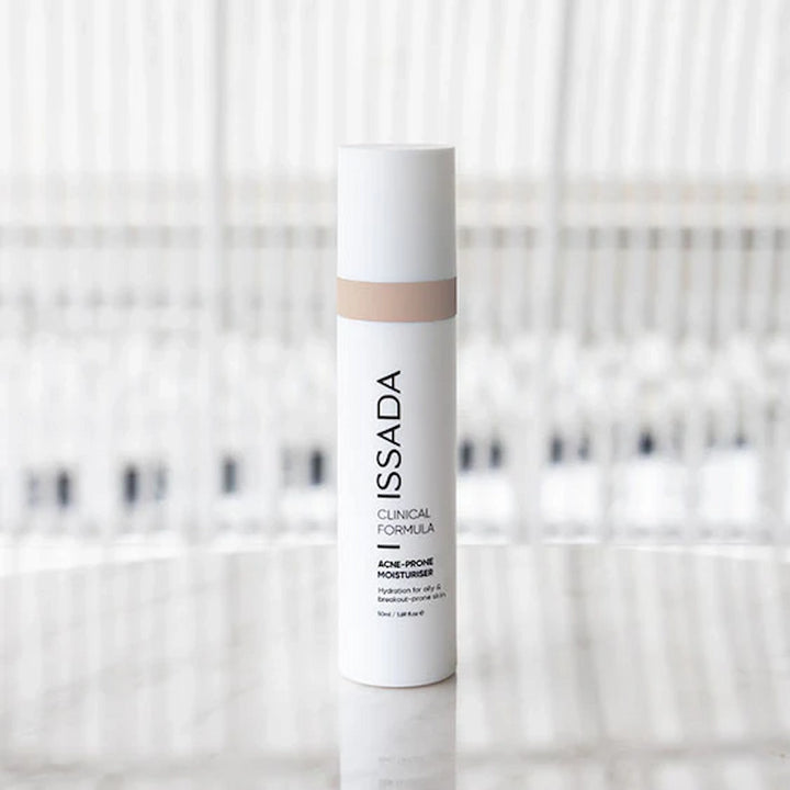 ISSADA Clinical Formula Acne-Prone Moisturiser bottle standing on reflective surface.