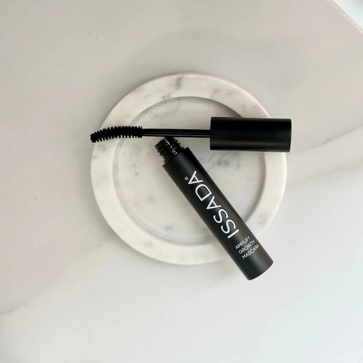 ISSADA Amplify Growth Mascara with curved wand on marble dish