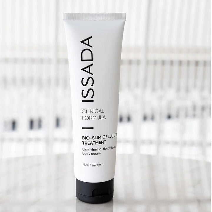 Tube of ISSADA Bio-Slim Cellulite Treatment body cream standing upright on a reflective surface.