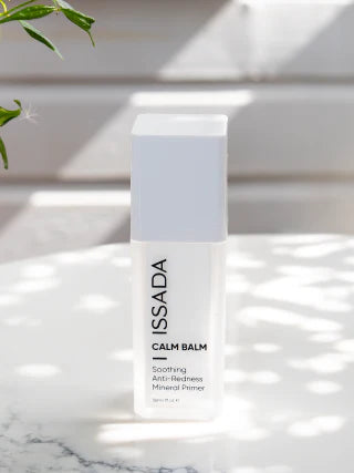 Issada Calm Balm Anti-redness Mineral Primer standing on marble with natural sunlight, soothing makeup base for calm, radiant skin