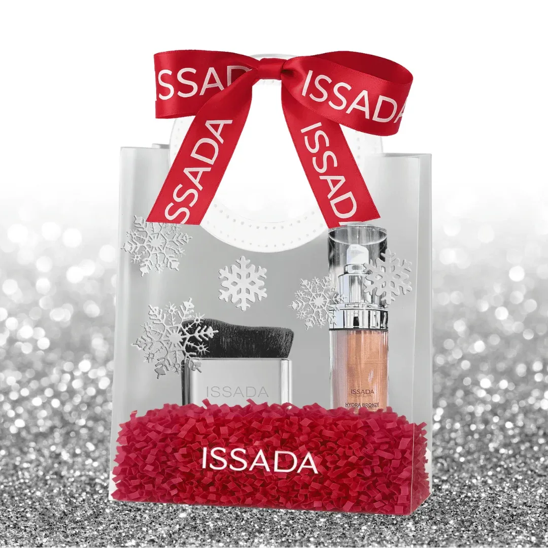 Clear Issada gift bag with red ribbon, snowflake design, and hydrating makeup essentials including brush and glow serum.