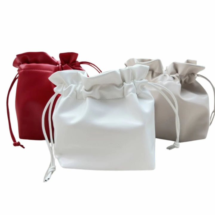 Three Issada drawstring makeup bags in red, white, and nude, designed for stylish cosmetic storage.