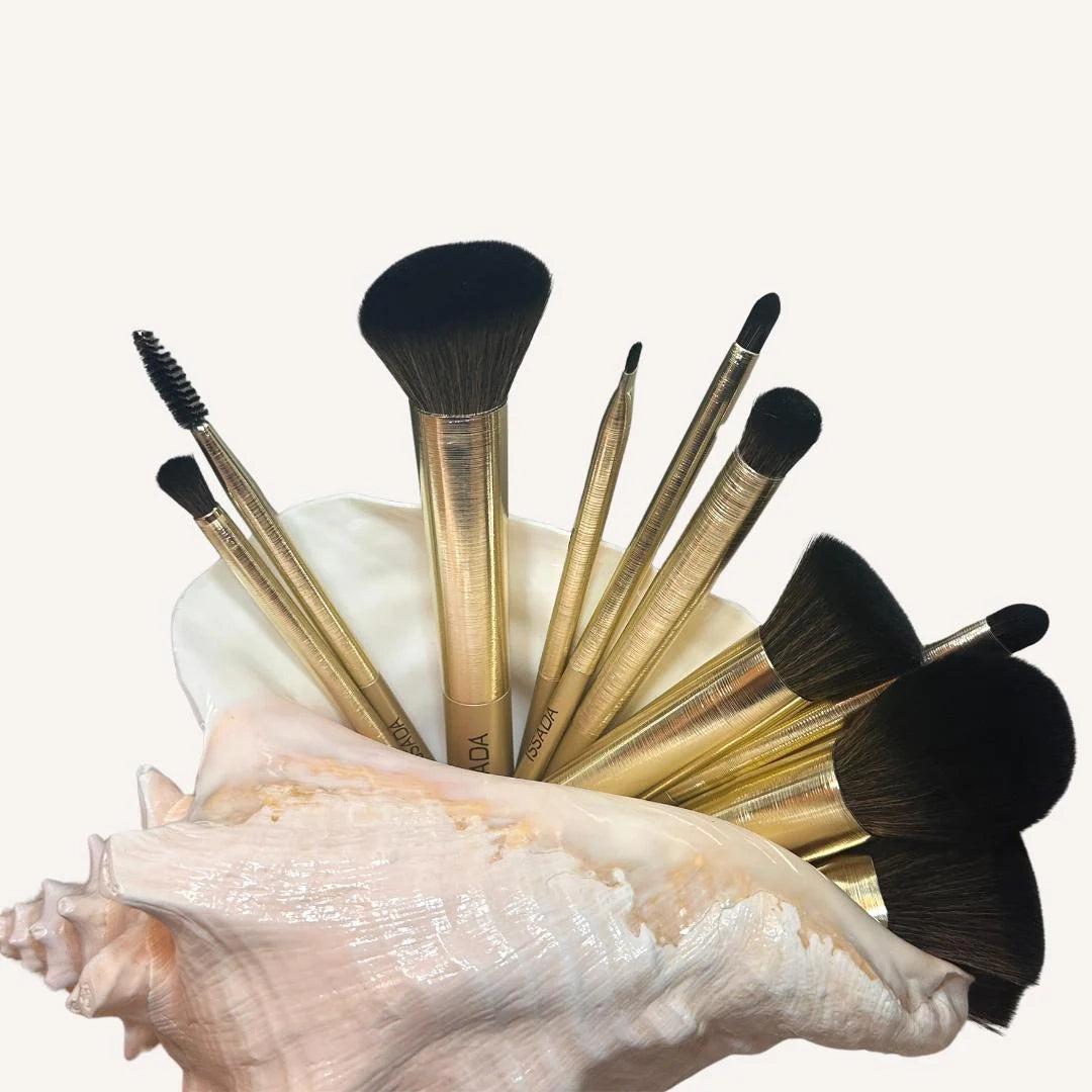 Issada Gold Professional Makeup Brush Set with sleek golden handles displayed in a seashell, featuring face and eye brushes.