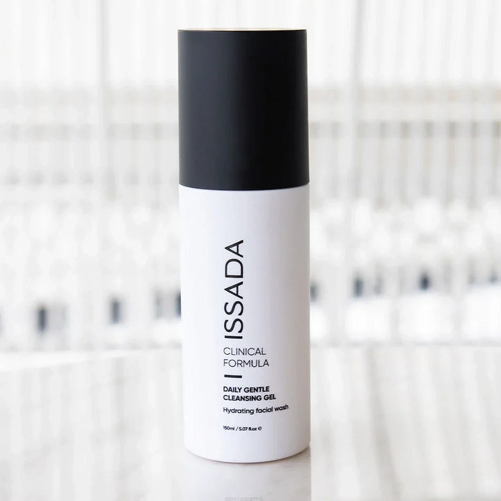 ISSADA Daily Gentle Cleansing Gel bottle on a marble counter with blurred background