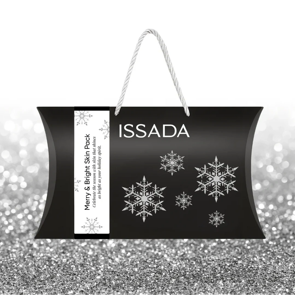 Issada Merry & Bright Skin Pack black festive gift bag with silver snowflakes and white rope handles, displayed on a silver glitter background.