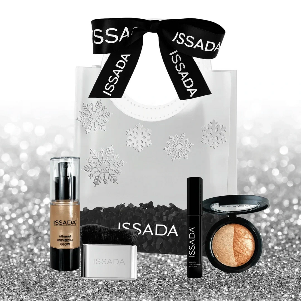 Issada Midnight Magic Collection displayed outside the gift bag with glow serum, compact baked highlighter, mascara, and brush on a silver glitter background.