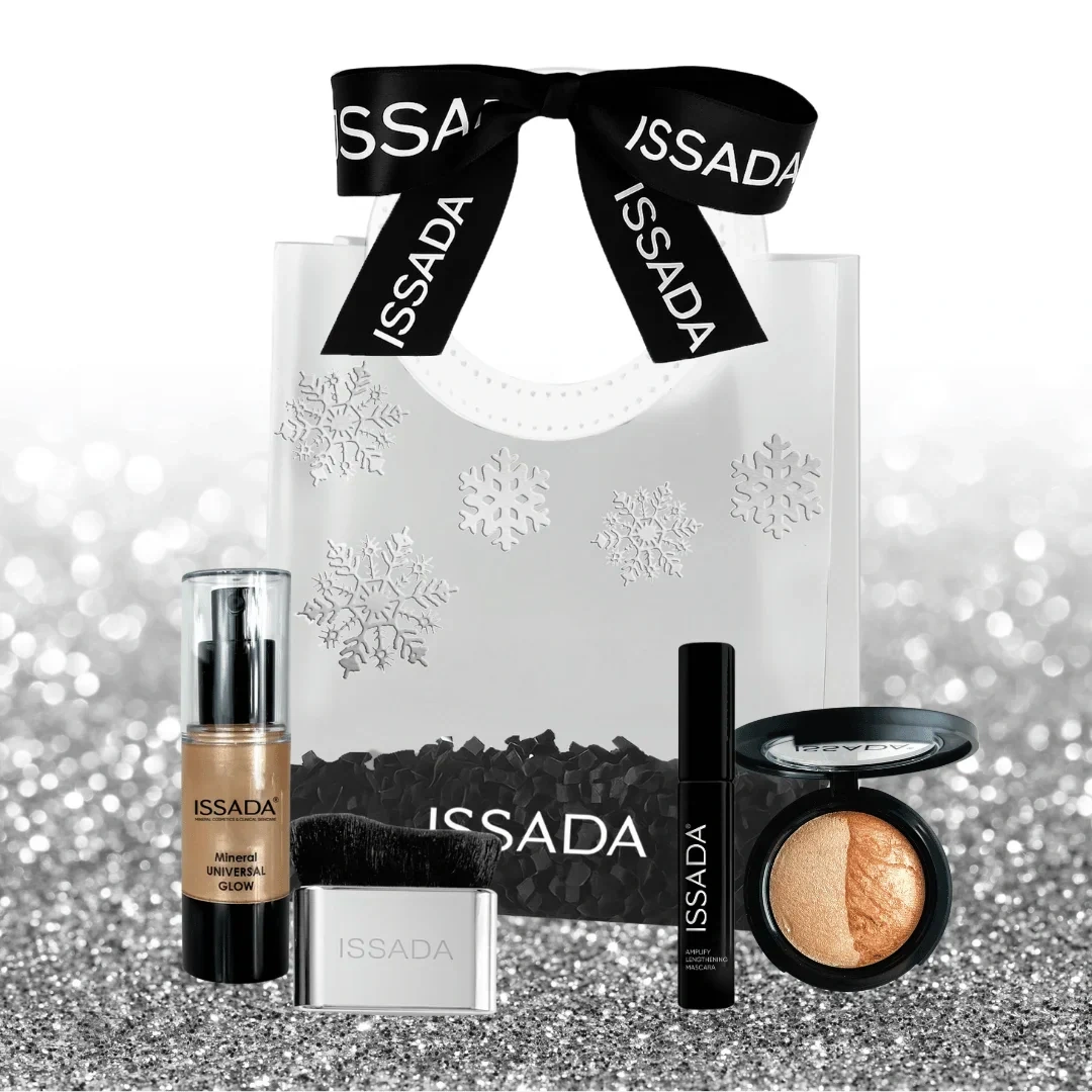 Issada Midnight Magic Collection displayed outside the gift bag with glow serum, compact baked highlighter, mascara, and brush on a silver glitter background.