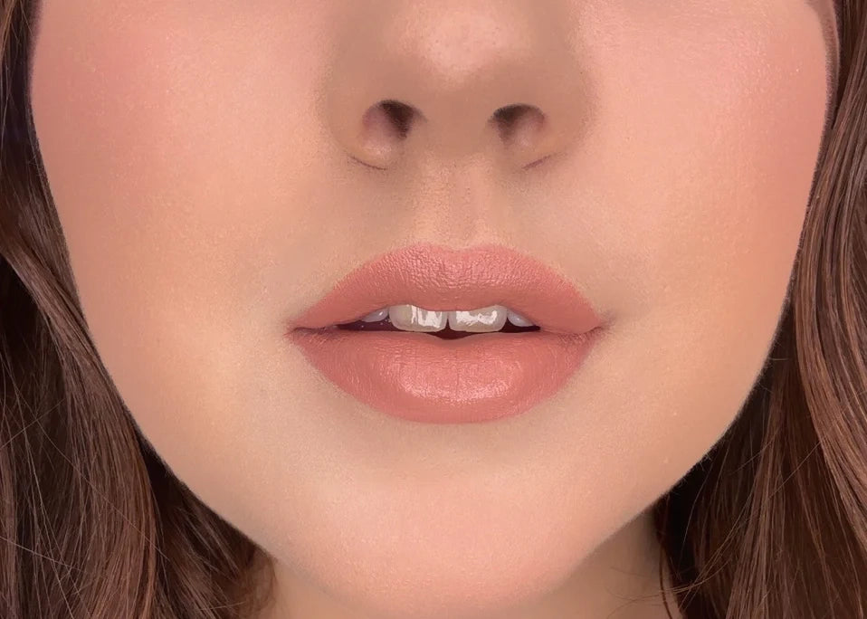 Close-up of a woman's lips with ISSADA Mineral Lip Crayons in Content shade, a soft peach nude with a creamy, moisturising finish.