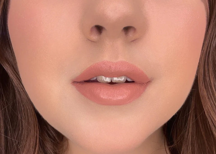 Close-up of a woman's lips with ISSADA Mineral Lip Crayons in Content shade, a soft peach nude with a creamy, moisturising finish.