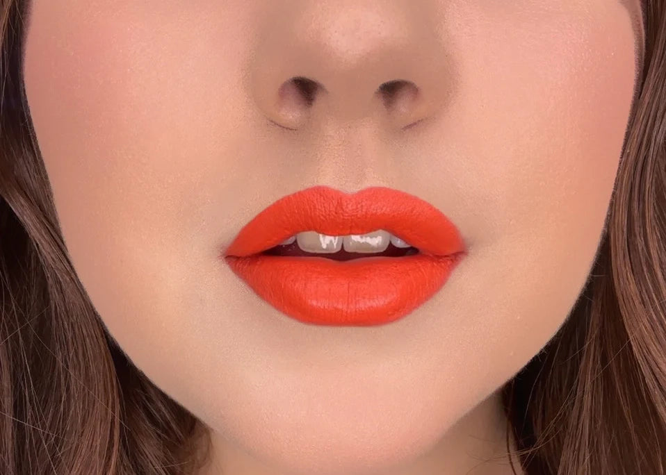 Close-up of model wearing ISSADA Mineral Lip Crayons in Euphoria shade, a bold vibrant orange-red lip with a creamy, soft-matte finish.