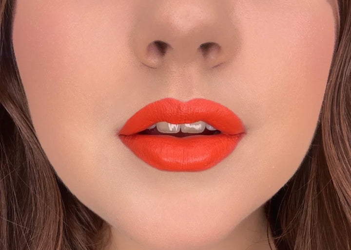 Close-up of model wearing ISSADA Mineral Lip Crayons in Euphoria shade, a bold vibrant orange-red lip with a creamy, soft-matte finish.