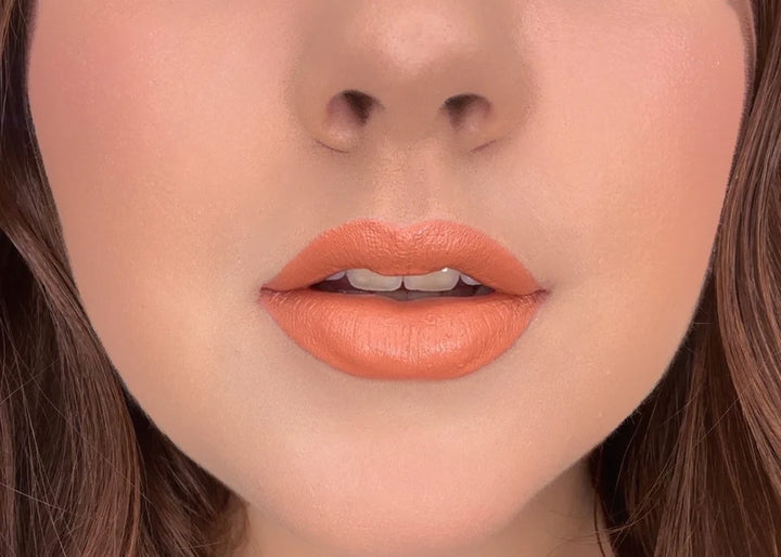 Close-up of a person's lips with ISSADA Mineral Lip Crayons in Modesty shade, a warm peachy nude with a smooth soft-matte finish.