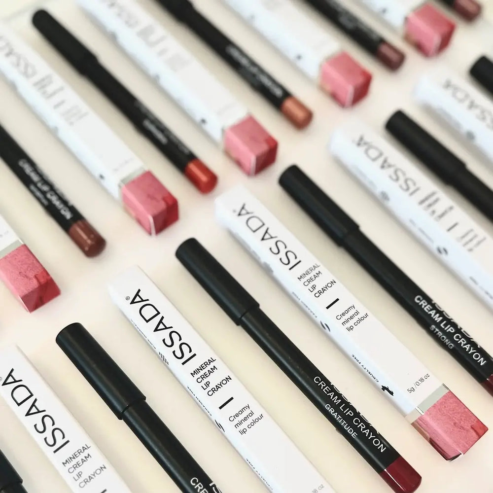 Collection of ISSADA Mineral Lip Crayons with various shades on a beige background