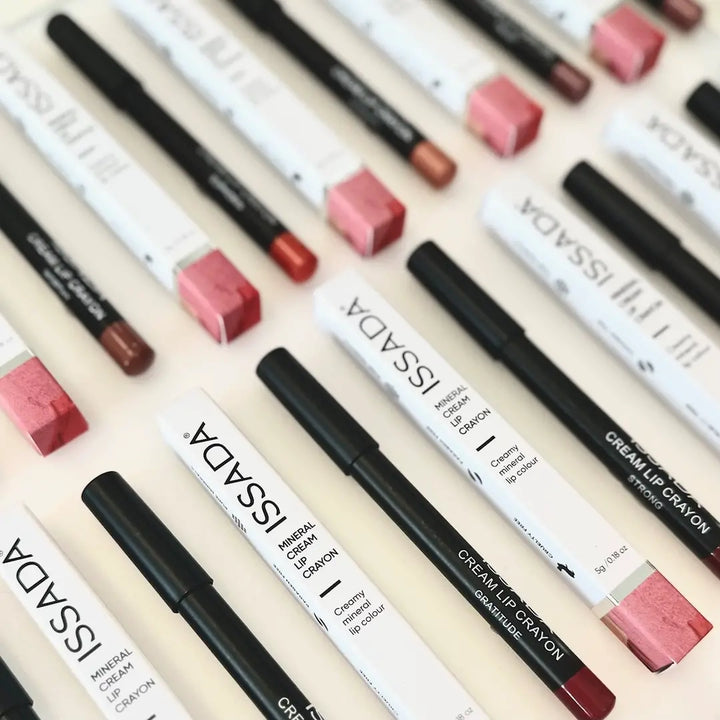 Collection of ISSADA Mineral Lip Crayons with various shades on a beige background