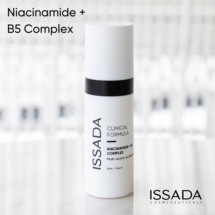 Issada Niacinamide + B5 Complex Clinical Formula serum bottle displayed on a reflective surface with a soft blurred background, showcasing the minimalist skincare packaging design.