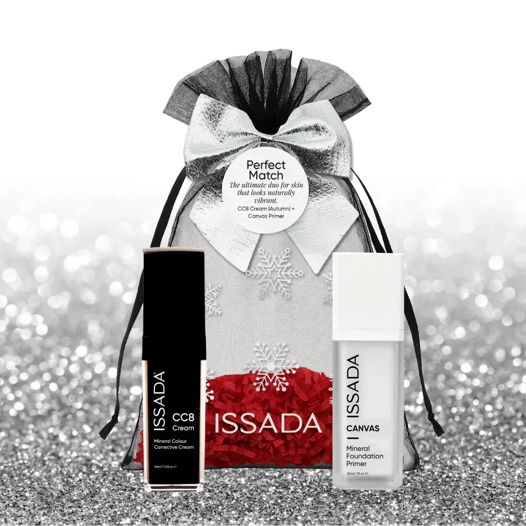 Issada silver festive gift bag with snowflake design and bow, displayed with CC8 Cream and Canvas Primer on a glitter background.