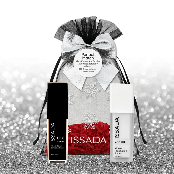 Issada silver festive gift bag with snowflake design and bow, displayed with CC8 Cream and Canvas Primer on a glitter background.