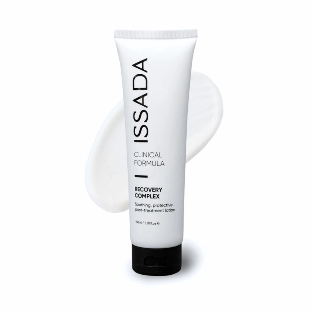 Issada Recovery Complex clinical formula tube displayed with a soft cream swatch behind it highlighting the soothing post treatment lotion texture