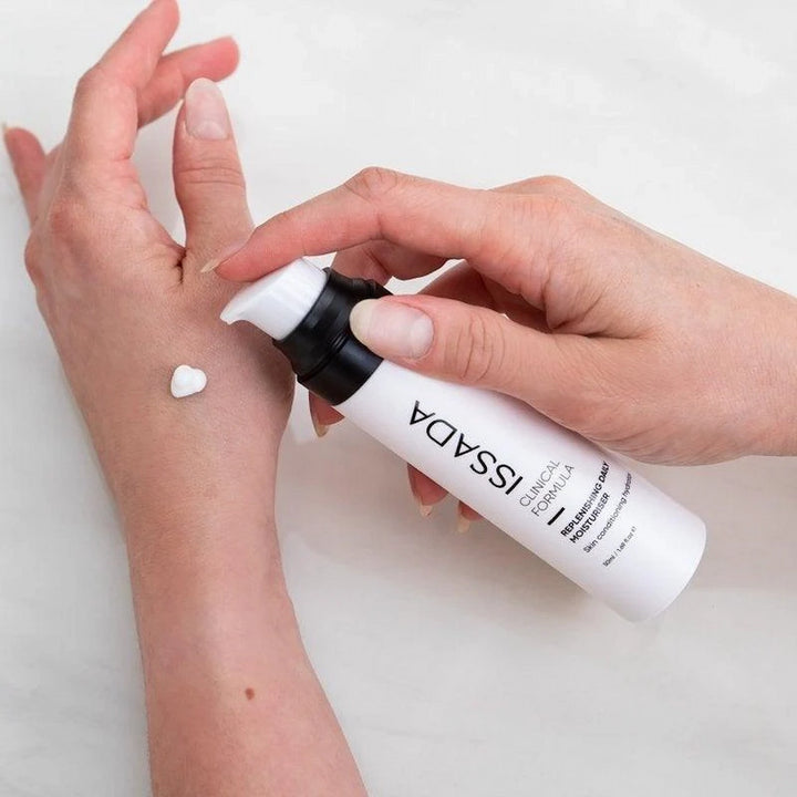 Hands applying ISSADA Replenishing Daily Moisturiser on a white background