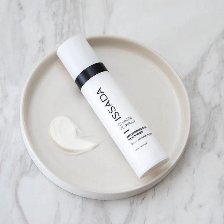 ISSADA Replenishing Daily Moisturiser  with cream swatch on a round dish over marble surface.