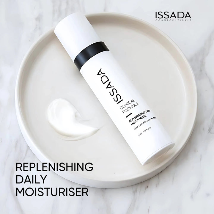 Issada Replenishing Daily Moisturiser bottle displayed on a white dish with cream texture, showcasing its smooth and hydrating formula.