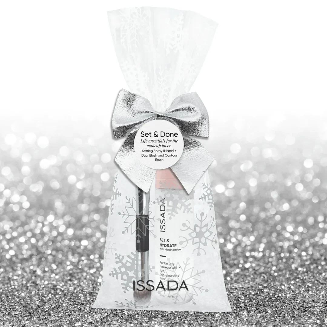 Issada Set & Done gift pack featuring a matte setting spray and dual blush contour brush in a frosted snowflake bag with silver bow on a glitter background.