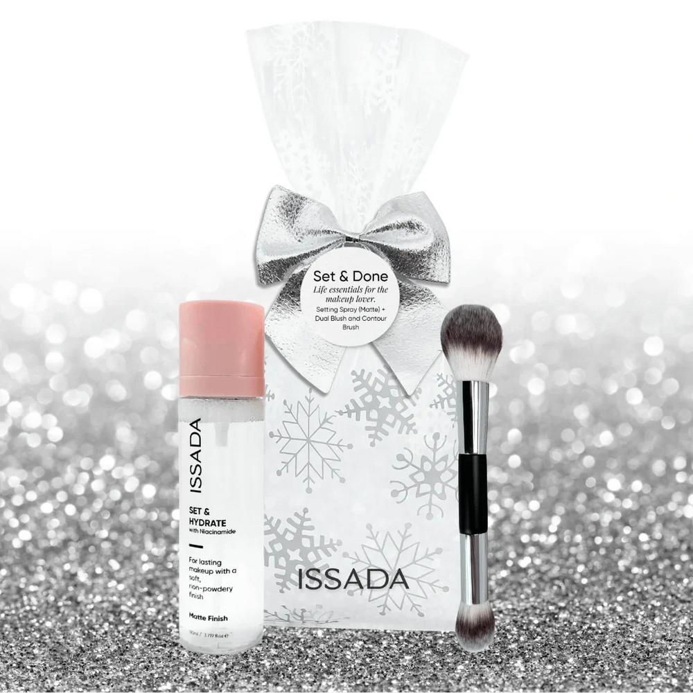 Issada Set & Done pack including a matte finish Set & Hydrate spray with niacinamide and a dual-ended blush and contour brush, styled with silver bow and snowflake bag on glitter background.