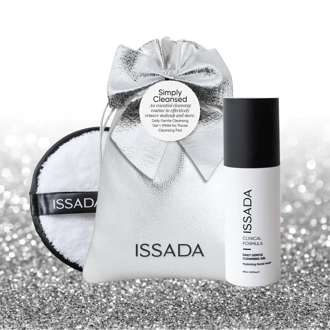 Issada Simply Cleansed set featuring Daily Gentle Cleansing Gel and White No Traces Cleansing Pad in a silver pouch with bow on a glitter background.