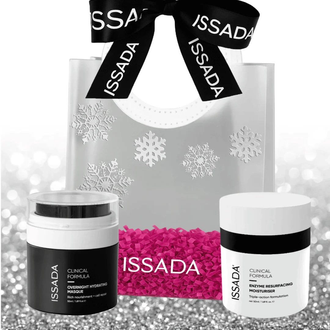Issada holiday gift bag with black ribbon, Overnight Hydrating Masque, and Enzyme Resurfacing Moisturiser displayed on silver glitter background.
