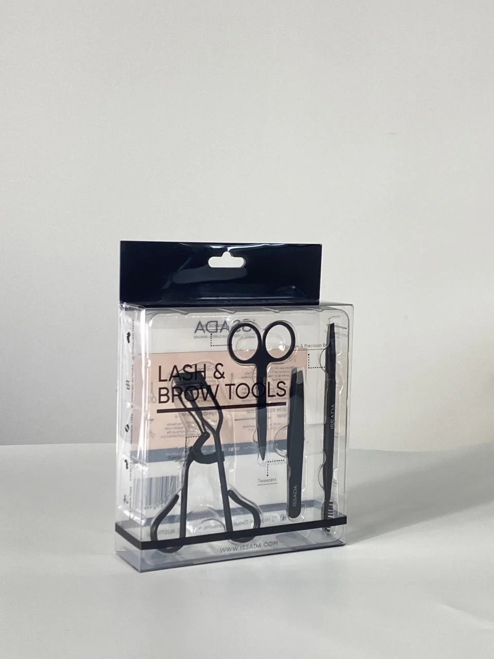 Issada Lash and Brow Tools set in clear packaging, featuring eyelash curler, brow scissors, tweezers, and spoolie brush.