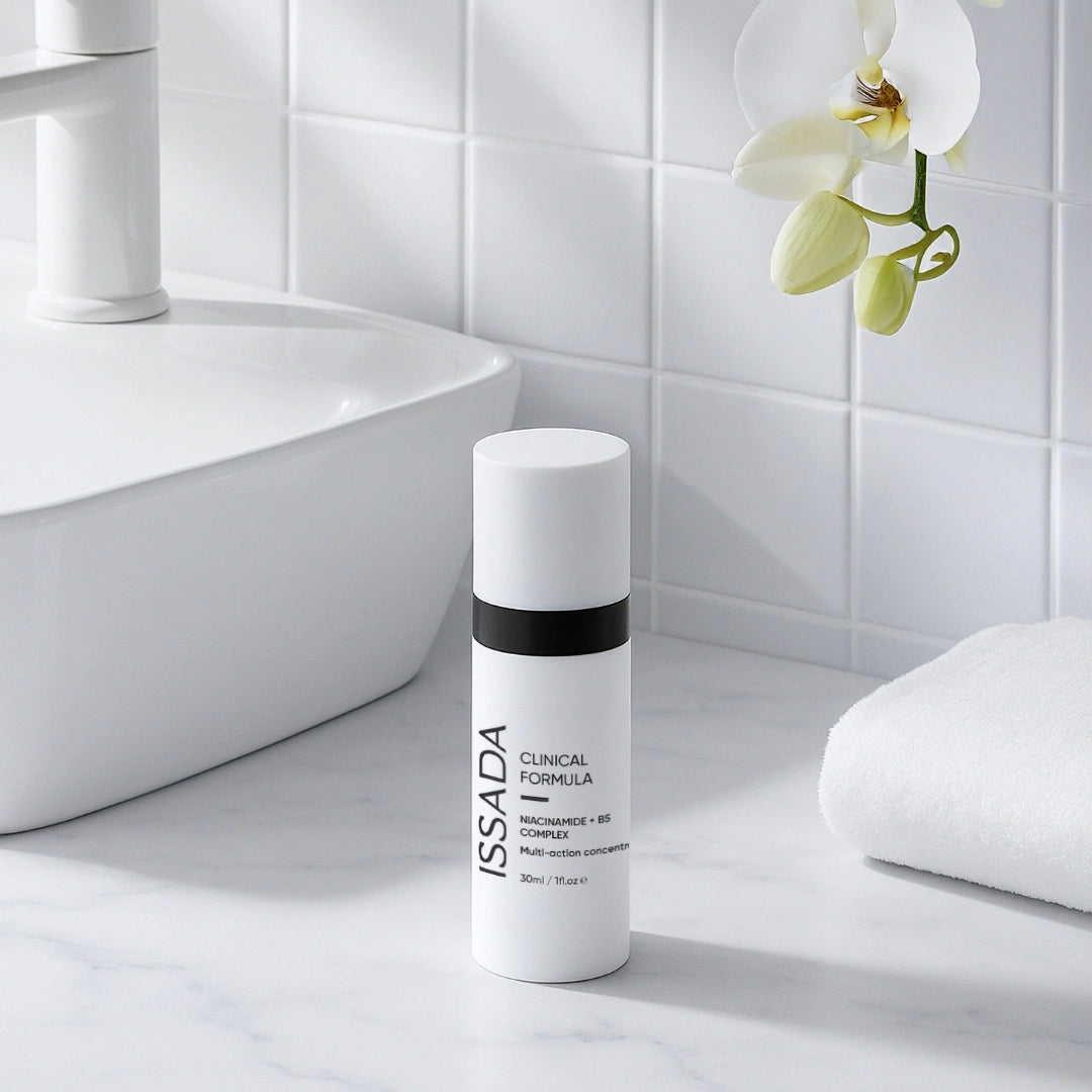 ISSADA Niacinamide + B5 Complex bottle on a bathroom counter beside a white towel and orchid.