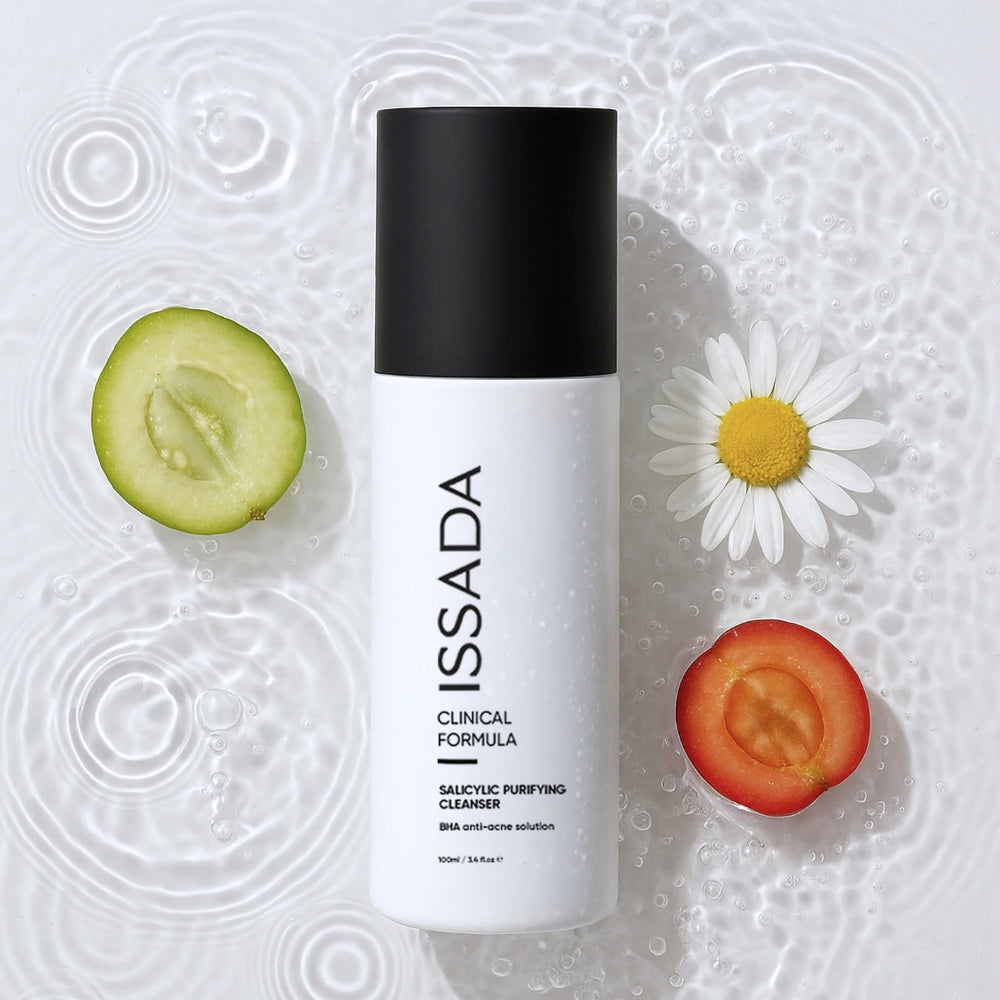 ISSADA Salicylic Purifying Cleanser bottle surrounded by fruit slices, chamomile and water ripples.
