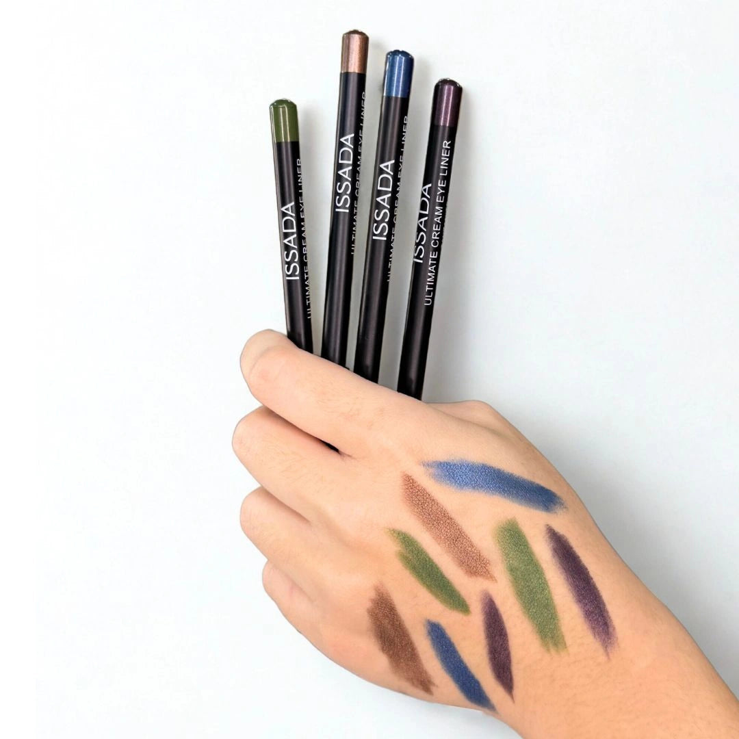 Hand holding four ISSADA Ultimate Eye Liner pencils with swatches on skin.
